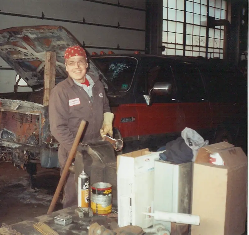 Crew member with a bandana in the shop, work table with tools.