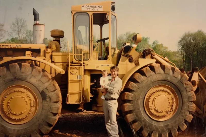 Worker beside a giant CAT wheel loader tire, scale shot.