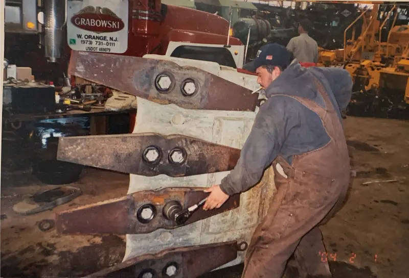 Crew member servicing bucket teeth in the shop.