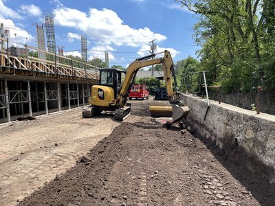 CAT mini-excavator working next to the board-form retaining wall during install.