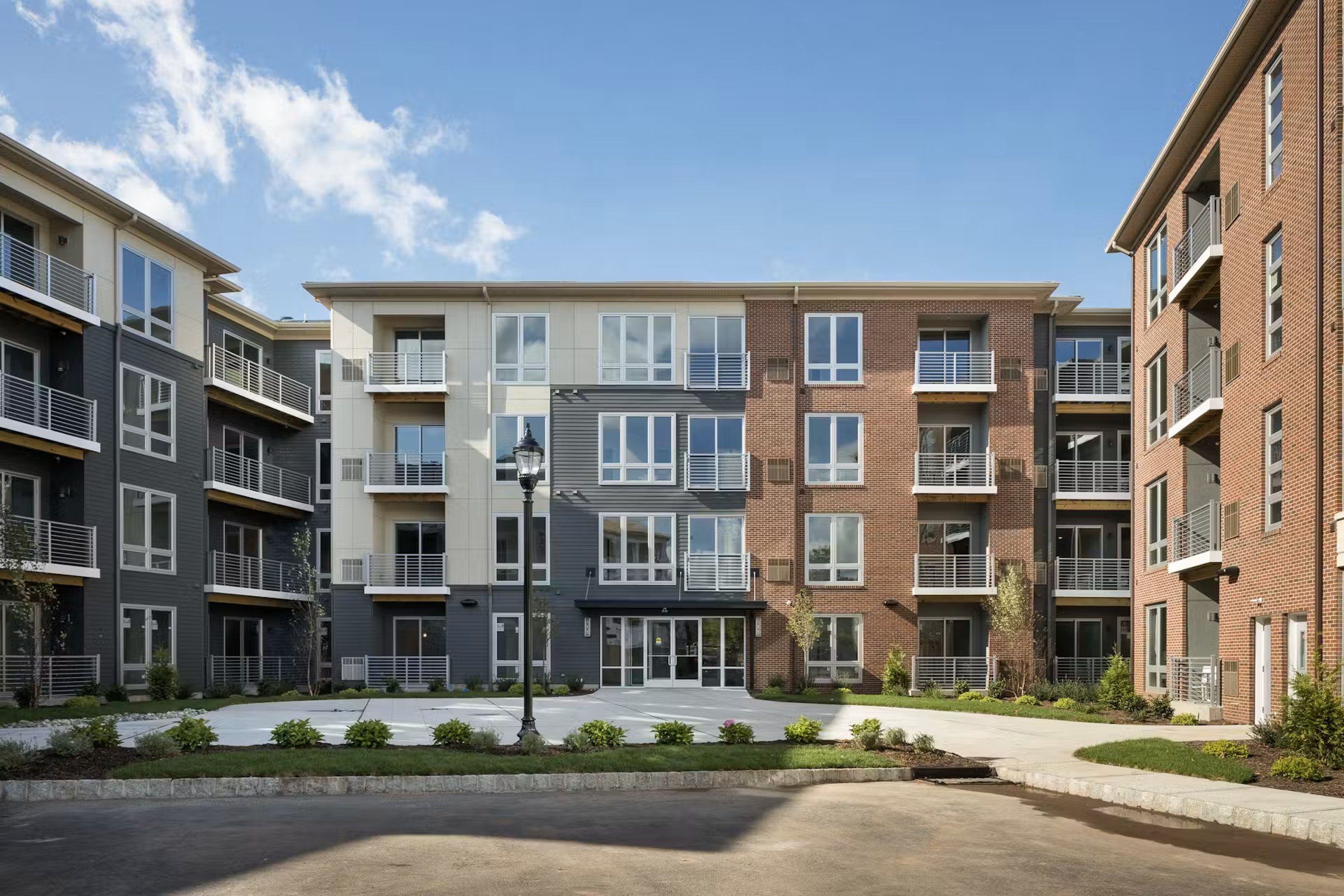 Quin Sleepy Hollow — completed exterior of the multifamily mid-rise with central courtyard view, mixed brick and panel facades.