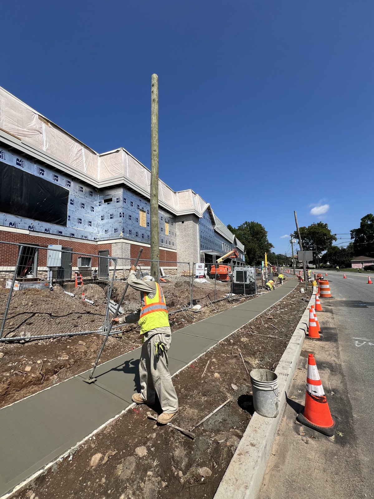 Concrete sidewalk pour along the red-brick facade.