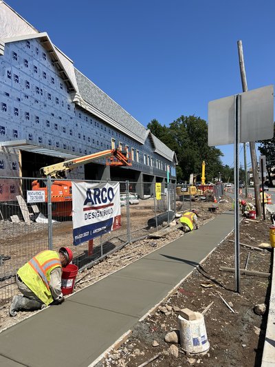 ARCO Design/Build banner on site during a concrete sidewalk pour.