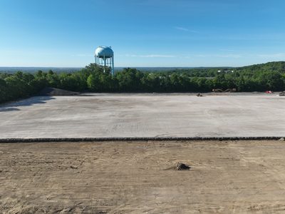 Wide view across the finished graded pad toward the water tower on the horizon.